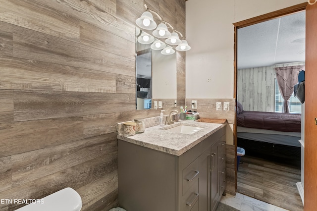 bathroom with vanity, toilet, and wooden walls