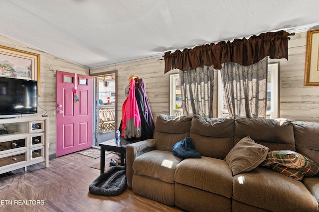 living room with wood-type flooring, a textured ceiling, wooden walls, and vaulted ceiling