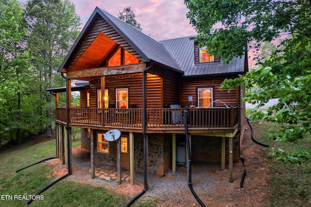 back house at dusk with a wooden deck and a patio area