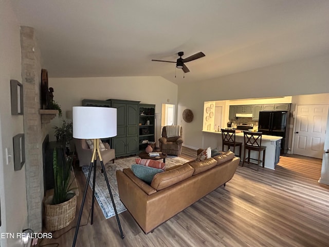 living room featuring ceiling fan, hardwood / wood-style flooring, lofted ceiling, and a fireplace