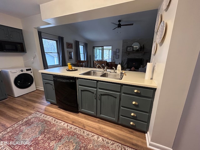 kitchen with washer / clothes dryer, kitchen peninsula, black appliances, vaulted ceiling, and light wood-type flooring