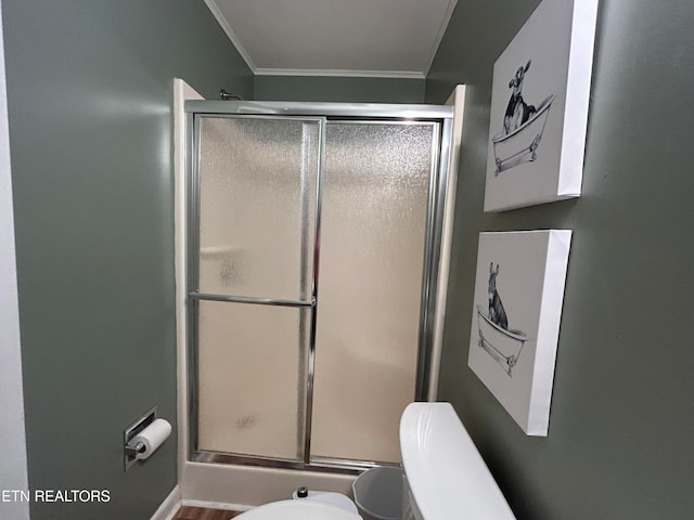 bathroom with toilet, ornamental molding, and an enclosed shower