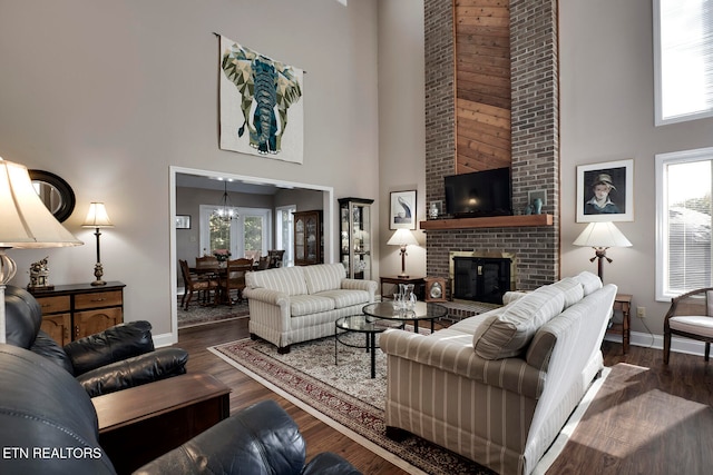 living room with a brick fireplace, dark hardwood / wood-style flooring, and a high ceiling