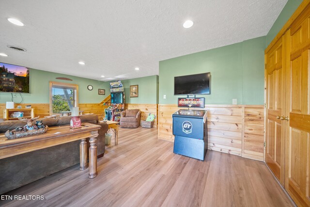 living room with wood walls, a textured ceiling, and hardwood / wood-style floors