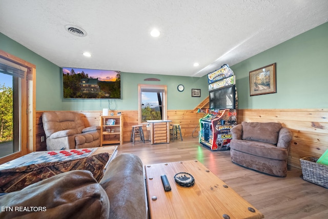 living room with hardwood / wood-style floors, a textured ceiling, and wooden walls