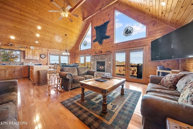 living room with a wealth of natural light, light hardwood / wood-style flooring, high vaulted ceiling, and wooden ceiling