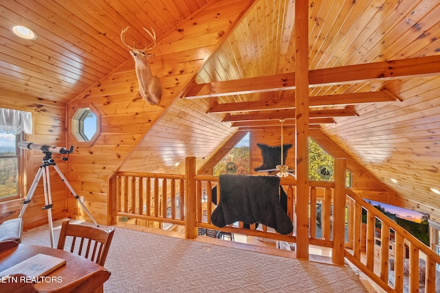 interior space with wooden walls, lofted ceiling with beams, wooden ceiling, and plenty of natural light