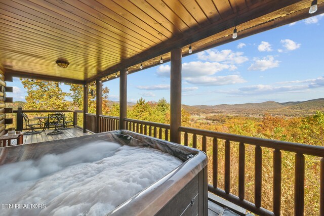 wooden deck with a hot tub and a mountain view