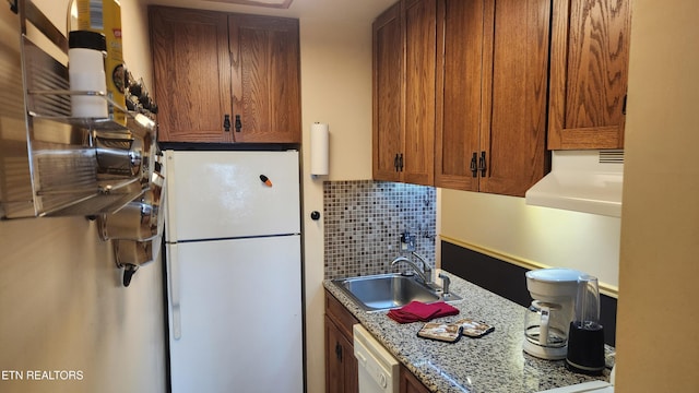 kitchen with tasteful backsplash, extractor fan, light stone countertops, sink, and white appliances