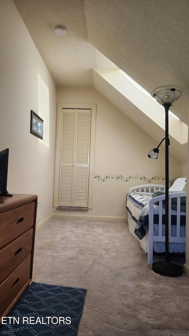 carpeted bedroom featuring lofted ceiling with skylight and a textured ceiling