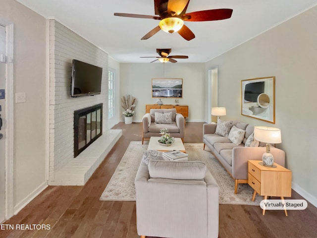 living room featuring ceiling fan, hardwood / wood-style flooring, and a brick fireplace