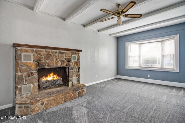 carpeted living room featuring beam ceiling, a stone fireplace, and ceiling fan