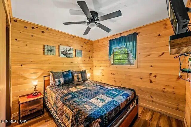 bedroom featuring ceiling fan, hardwood / wood-style floors, and wood walls