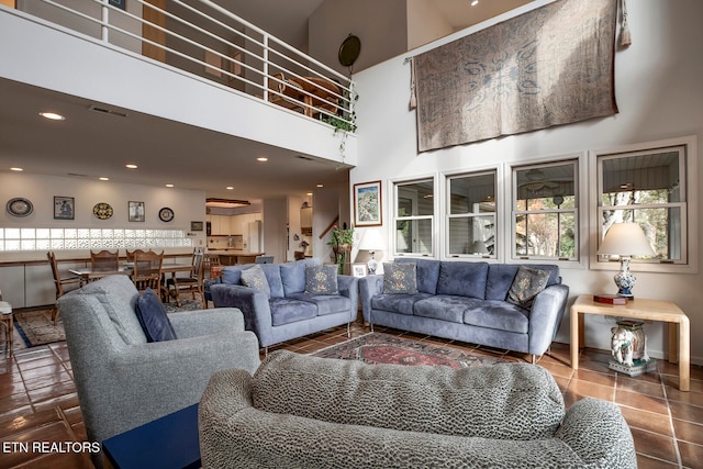 living room with a towering ceiling, recessed lighting, visible vents, and tile patterned floors