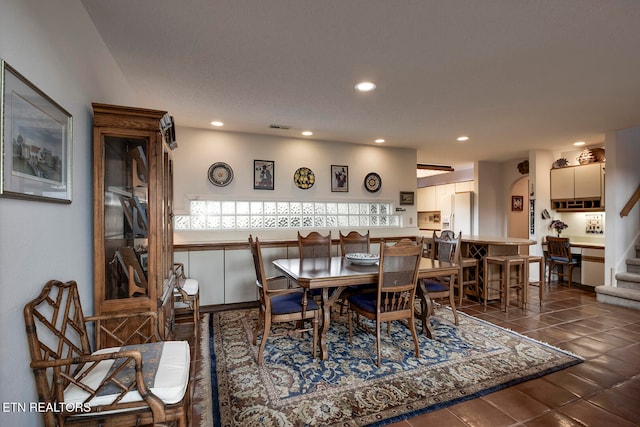 tiled dining area featuring arched walkways, recessed lighting, visible vents, and stairway