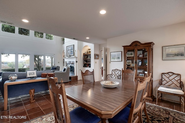 dining area featuring tile patterned flooring, visible vents, a tiled fireplace, and recessed lighting