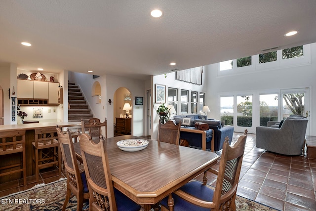 dining room featuring a textured ceiling, arched walkways, recessed lighting, visible vents, and stairs