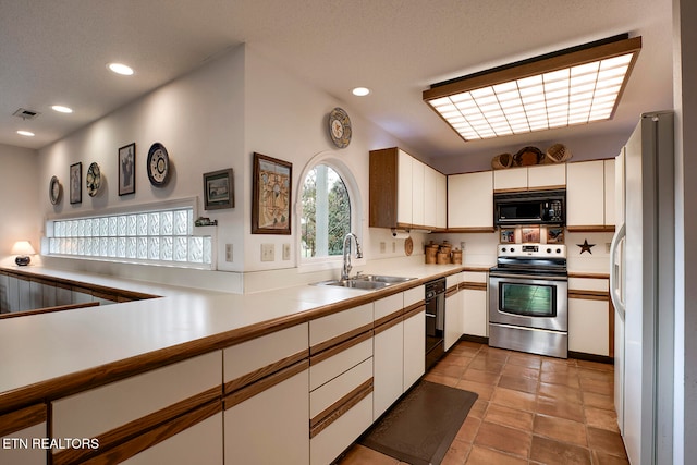 kitchen with a sink, visible vents, white cabinetry, light countertops, and black appliances