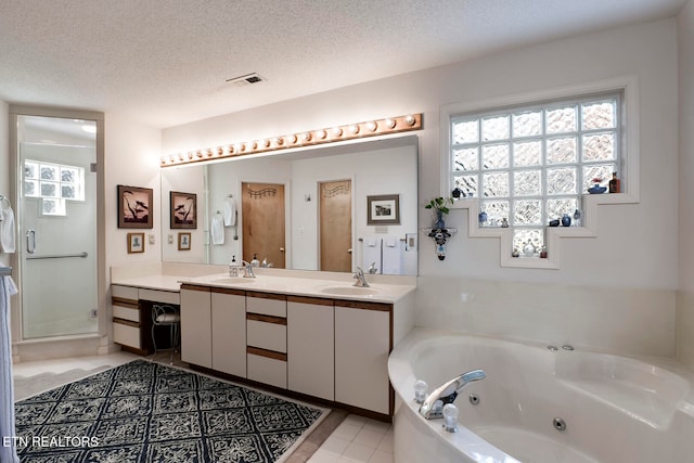 bathroom with visible vents, tile patterned floors, a whirlpool tub, a textured ceiling, and a sink