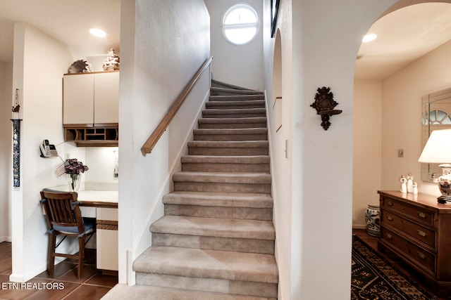 staircase with tile patterned flooring, arched walkways, baseboards, and recessed lighting