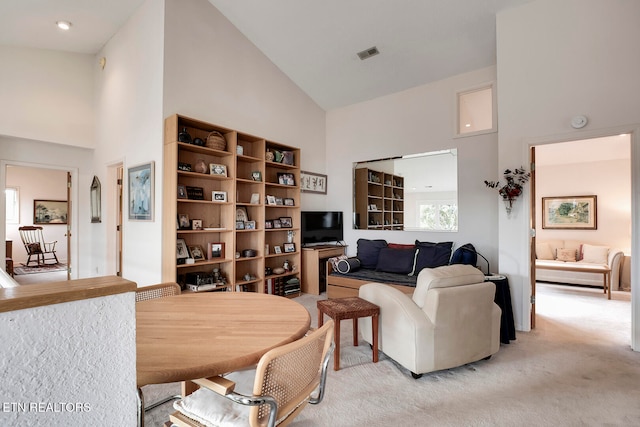 living room featuring high vaulted ceiling and light carpet