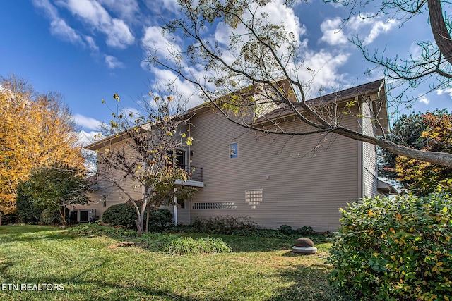 view of side of home with a yard and a balcony