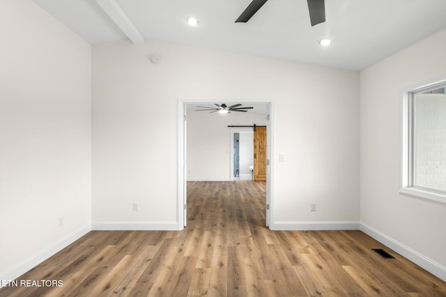 unfurnished room with light hardwood / wood-style flooring, a barn door, lofted ceiling with beams, and ceiling fan