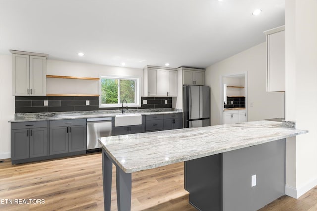 kitchen with appliances with stainless steel finishes, kitchen peninsula, a kitchen breakfast bar, and gray cabinets