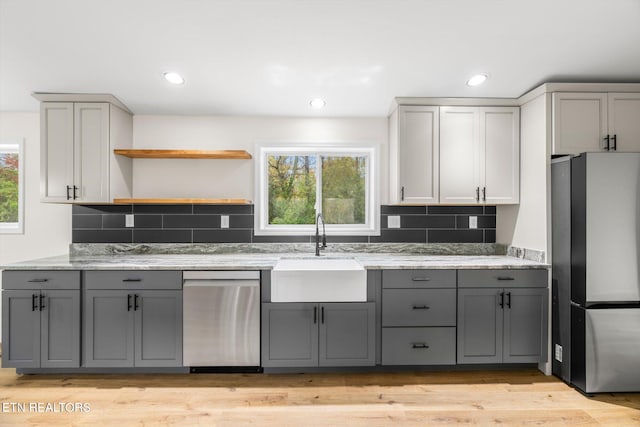 kitchen featuring gray cabinetry, appliances with stainless steel finishes, sink, backsplash, and light hardwood / wood-style flooring