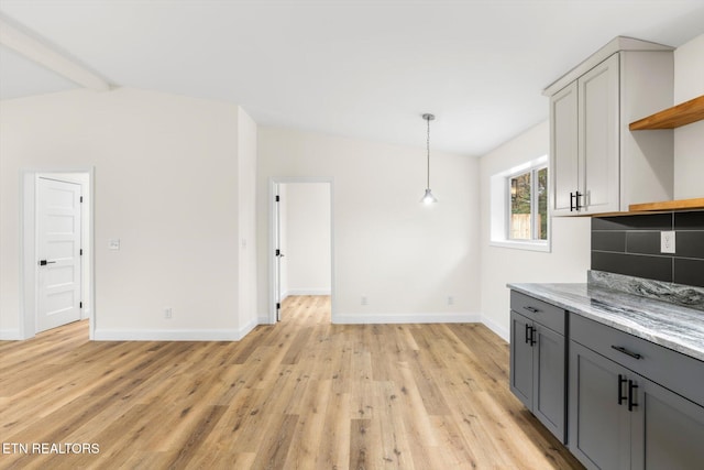 kitchen featuring light hardwood / wood-style floors, light stone countertops, vaulted ceiling with beams, and gray cabinetry