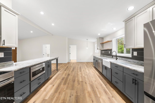 kitchen featuring white cabinetry, lofted ceiling with beams, sink, and light wood-type flooring