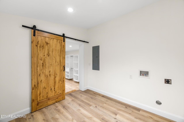 interior space featuring electric panel, light wood-type flooring, and a barn door