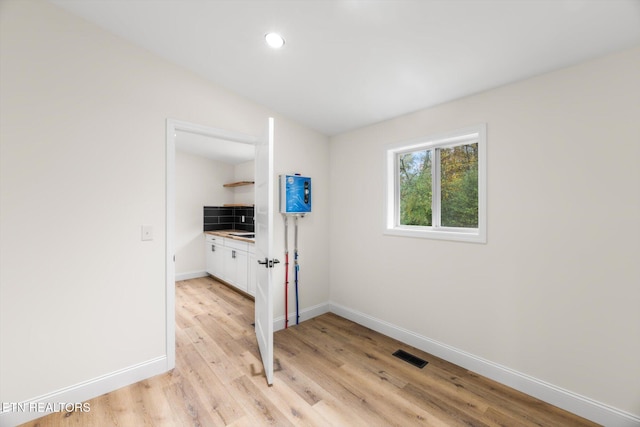 unfurnished room with light hardwood / wood-style floors and lofted ceiling