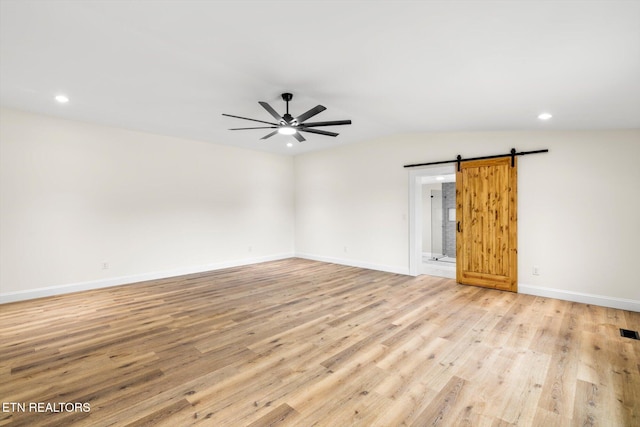 unfurnished room with ceiling fan, lofted ceiling, light hardwood / wood-style flooring, and a barn door