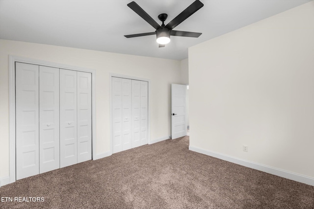 unfurnished bedroom with ceiling fan, carpet floors, and two closets