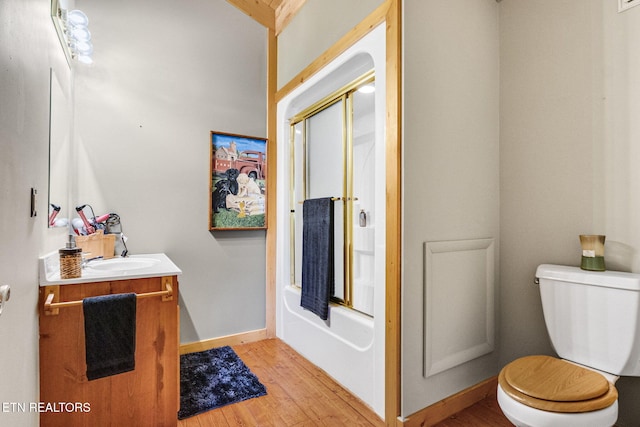 full bathroom with toilet, vanity, bath / shower combo with glass door, and hardwood / wood-style flooring