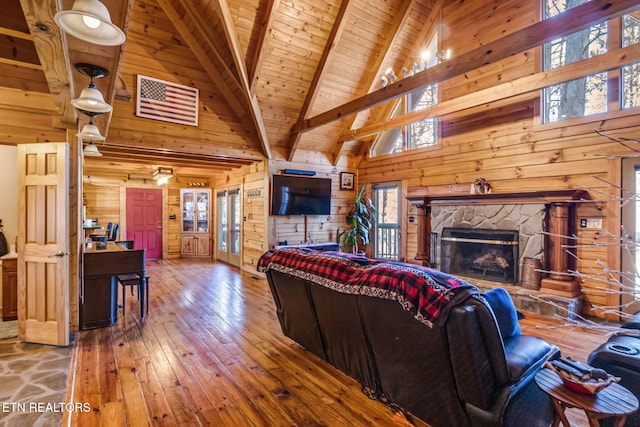 living room with wood-type flooring, wooden walls, wooden ceiling, high vaulted ceiling, and beamed ceiling