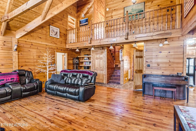 living room with wood-type flooring, beam ceiling, high vaulted ceiling, wooden walls, and wood ceiling