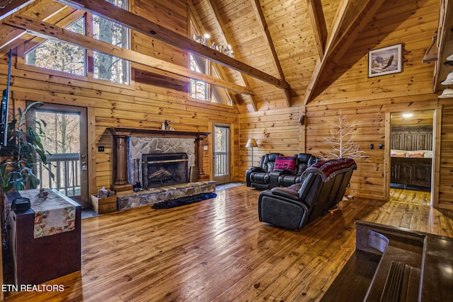 living room featuring wood-type flooring, wooden walls, and high vaulted ceiling