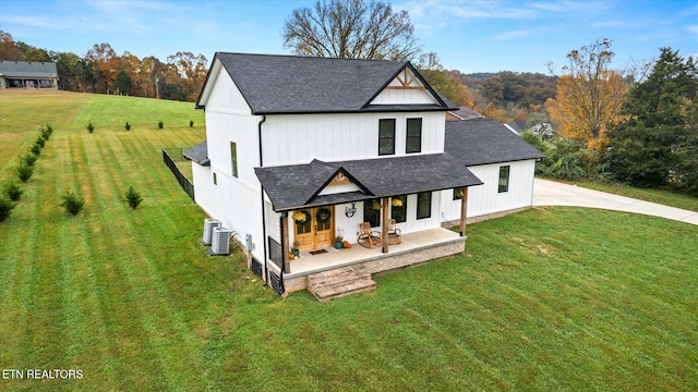 view of front facade featuring central AC, a front yard, and covered porch