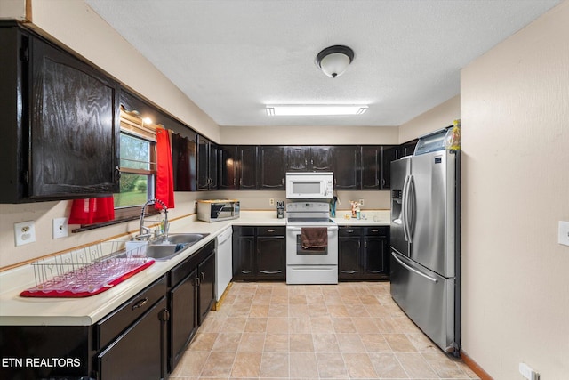 kitchen with white appliances, a textured ceiling, and sink