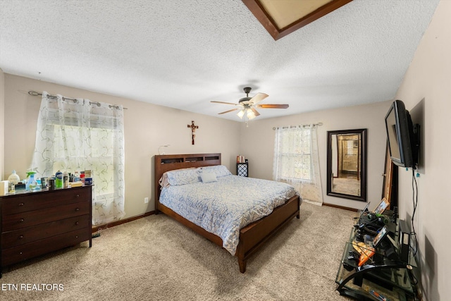 bedroom featuring light carpet, a textured ceiling, and ceiling fan