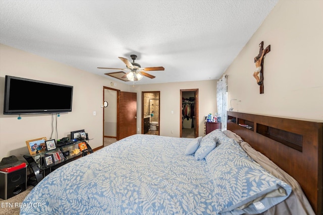 carpeted bedroom with a closet, a walk in closet, a textured ceiling, ensuite bathroom, and ceiling fan