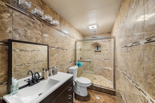 bathroom with toilet, an enclosed shower, vanity, and tile walls