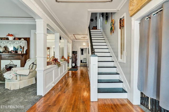 foyer featuring crown molding, ornate columns, and hardwood / wood-style flooring