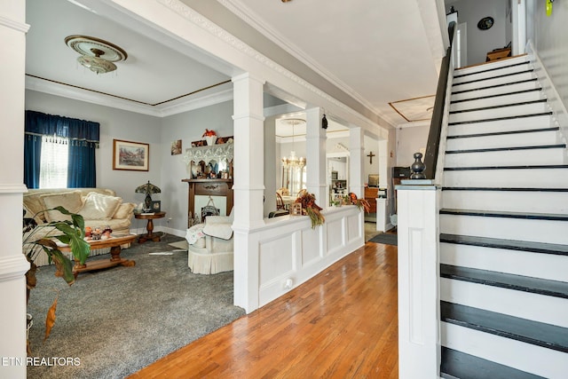 staircase featuring decorative columns, ornamental molding, and hardwood / wood-style floors