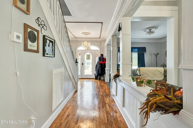 entrance foyer featuring a notable chandelier, ornamental molding, wood-type flooring, and ornate columns