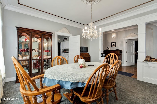 dining space featuring decorative columns, an inviting chandelier, ornamental molding, and dark colored carpet