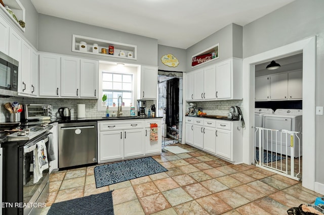 kitchen featuring decorative backsplash, stainless steel appliances, sink, white cabinetry, and washing machine and dryer