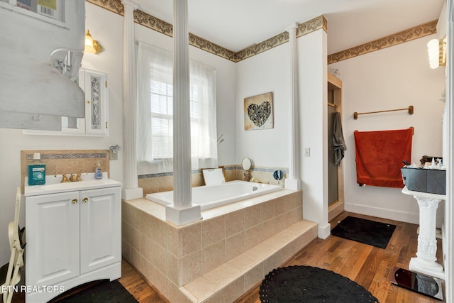 bathroom featuring vanity, tiled tub, and hardwood / wood-style flooring